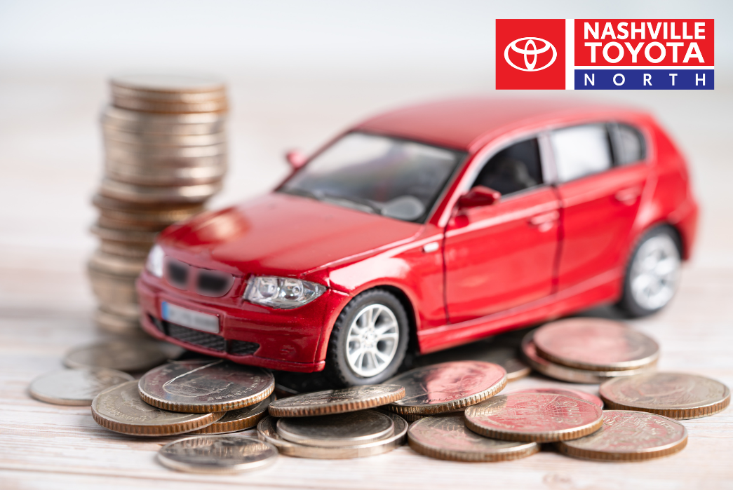A red car sits on top of stacks of coins