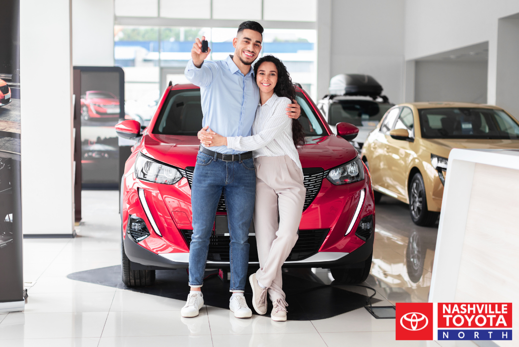 A person standing in front of a car in a showroom