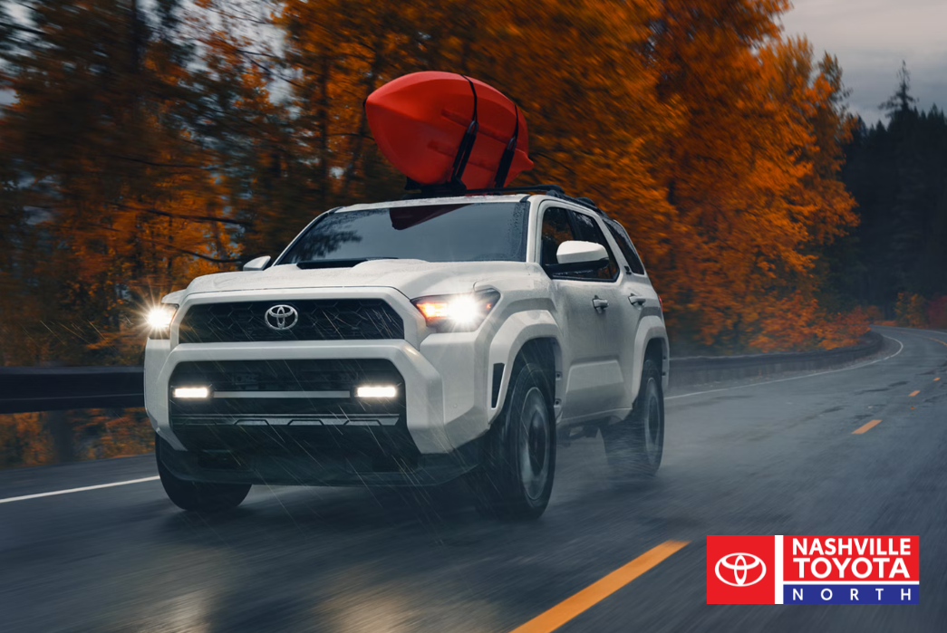 a toyota 4runner is driving down the road with a red kayak on the roof
